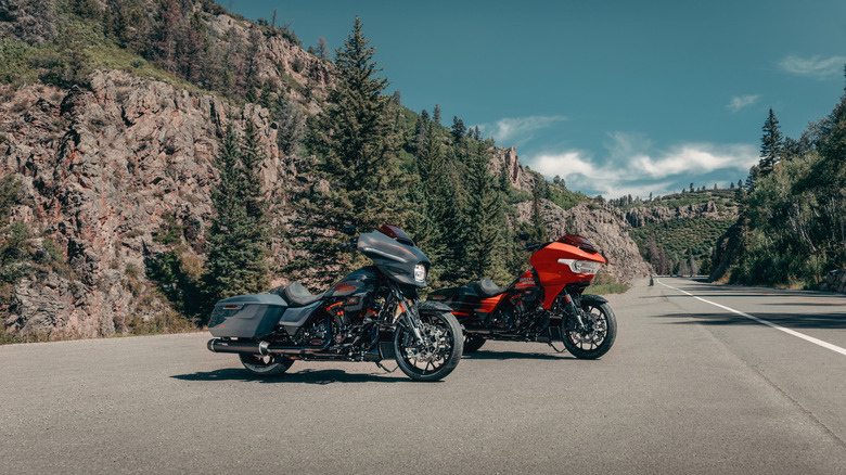 A black and a red 2026 Harley-Davidson CVO Road Glide ST motorbike parked at an angle on an empty stretch of highway in the afternoon sun.