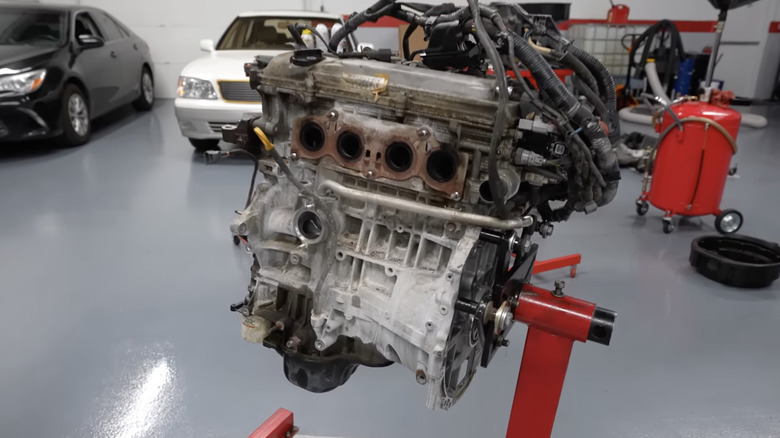 Toyota 2AZ-FE on an engine hoist in a car shop.