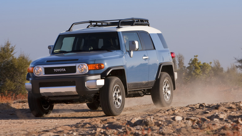 Front three-quarter view of blue Toyota FJ Cruiser driving on desert trail.