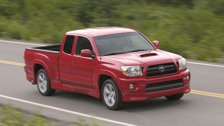 Front three-quarter view of red Toyota Tacoma X-Runner driving on rural road.