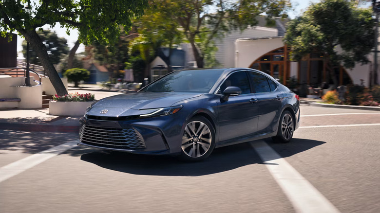 A dark blue 2026 Toyota Camry photographed while taking a corner in a suburban neighborhood.