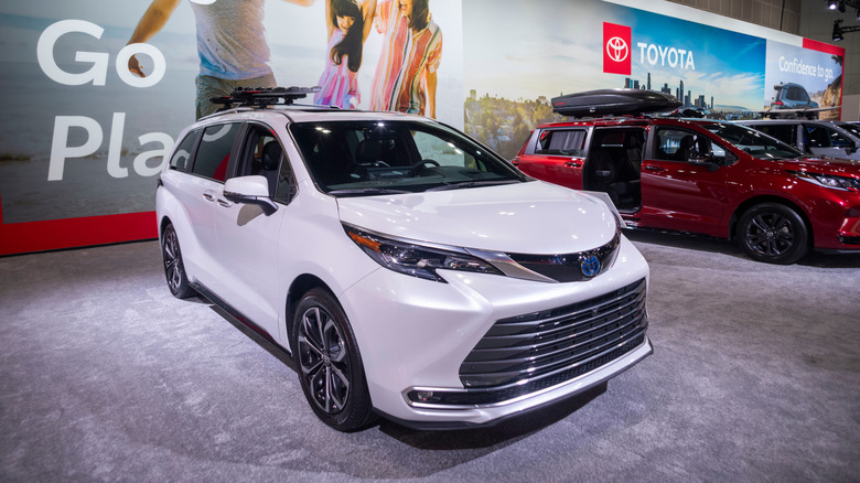 A white 2026 Toyota Sienna Platinum trim being shown at a podium at a 2025 auto show.