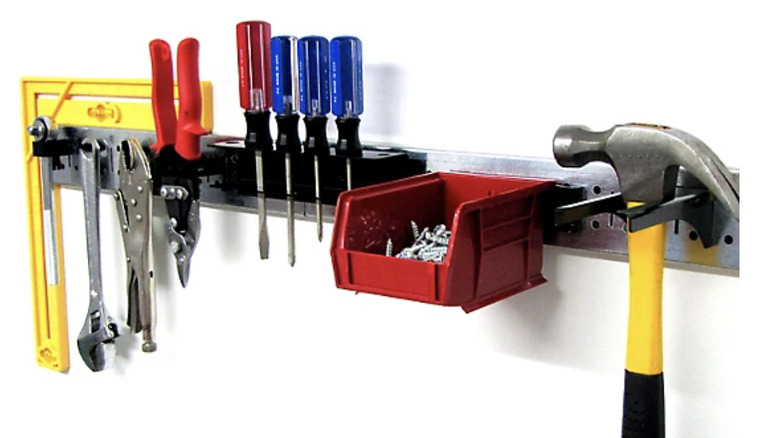A metal pegboard strip holding a variety of hand tools