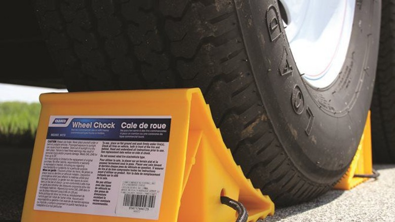 A trailer tire held up by a Camco wheel chock.