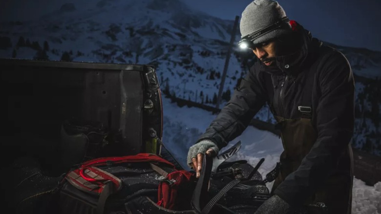A man wearing a COAST headlamp working outside in the snow.