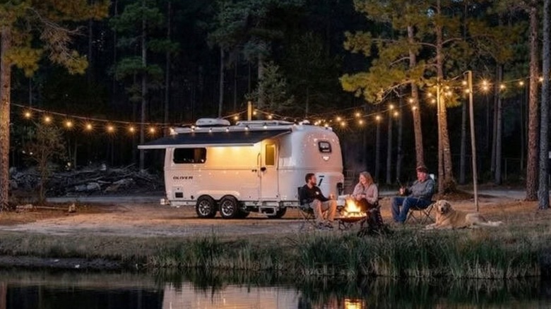 People around a campfire outside a parked Legacy Elite II campter