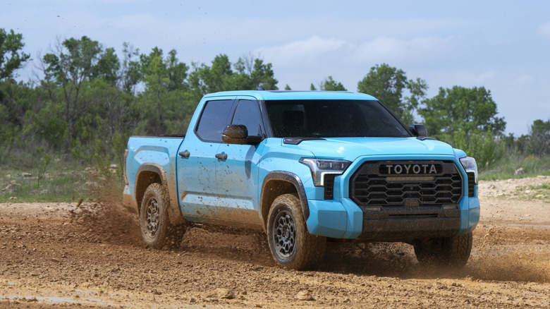 Light blue 2026 Toyota Tundra TRD Pro driving through muddy terrain at speed