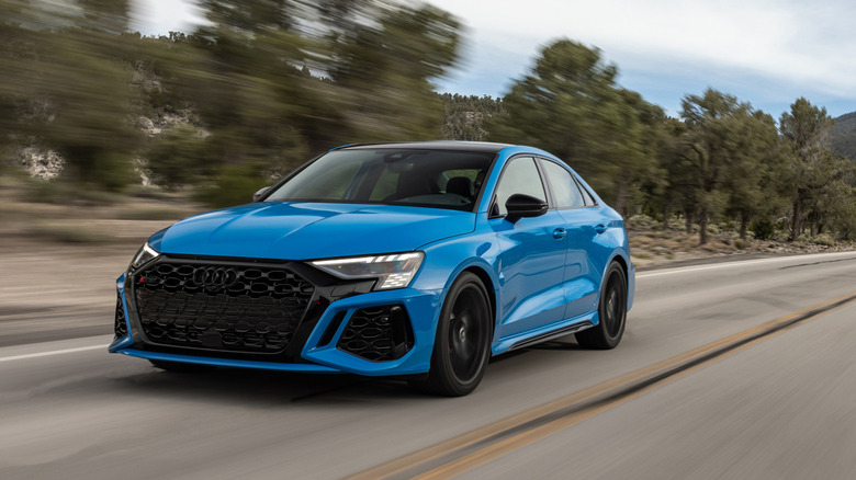 Front 3/4 view of blue Audi RS 3 driving on mountain road.