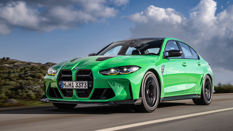 Front 3/4 view of green BMW M3 CS driving on country road.