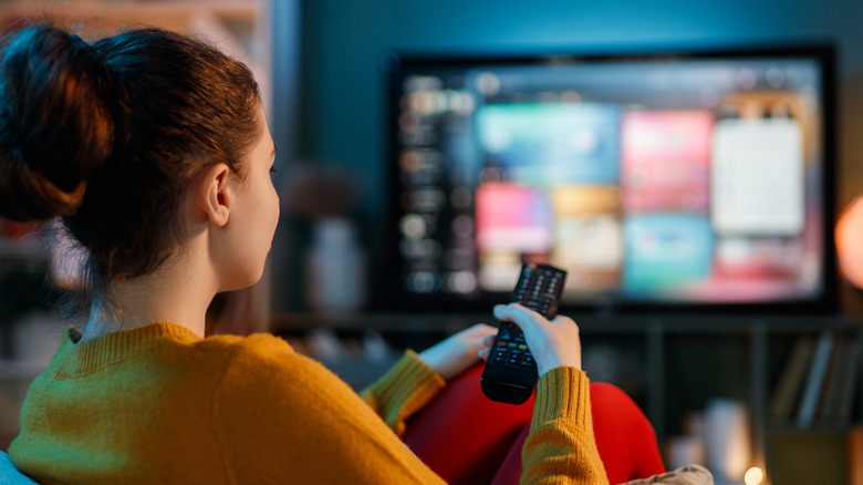 Young woman watching TV at home.