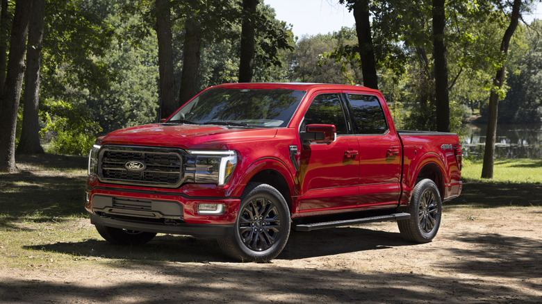 Front 3/4 view of a red Ford F-150 Lariat with some trees in the background