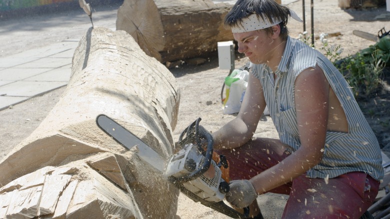 Sculptor cutting tree with chainsaw