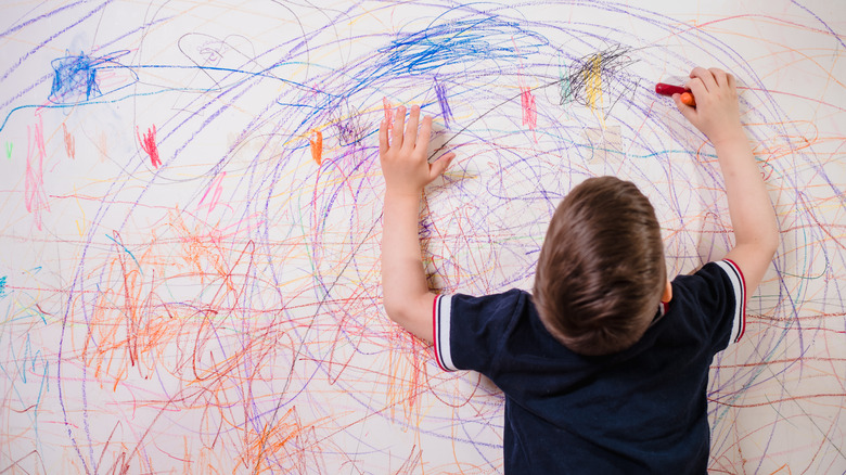 Kid crayoning  on a wall