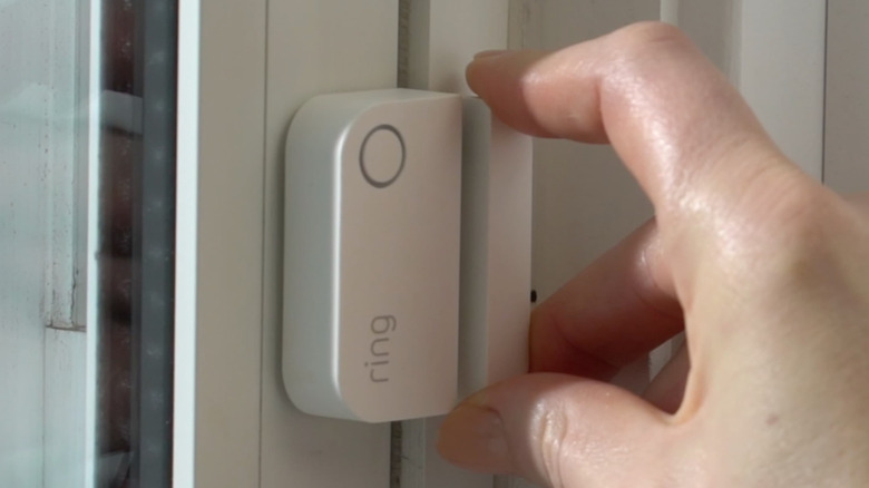Hand installing door sensor in window