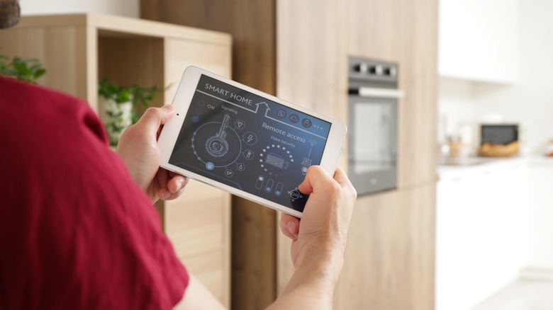 Hand holding tablet showing smart home dashboard