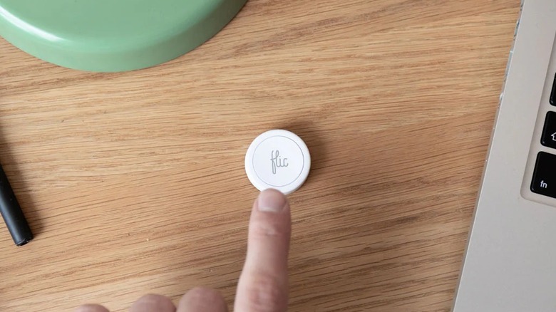 Finger pressing Flic smart button on table