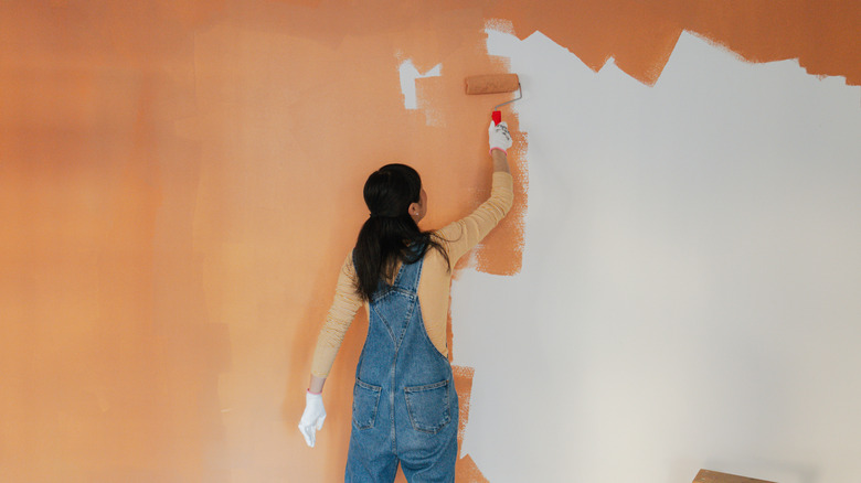 woman painting wall orange