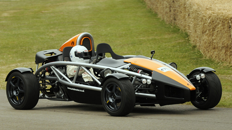 Black and yellow Ariel Atom 500 on track near green grass