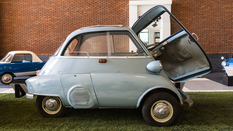 Grey BMW Isetta parked in front of brick wall with open door