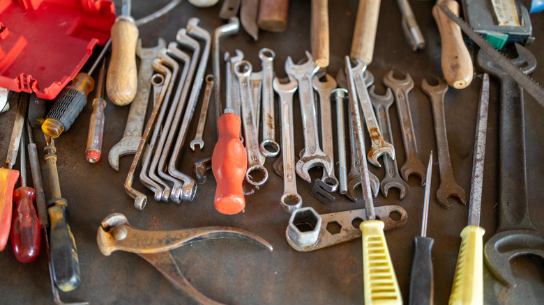 A collection of wrenches and other tools spread on a table.
