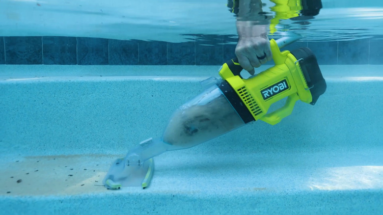 Hand submerging Ryobi Pool Vacuum into pool