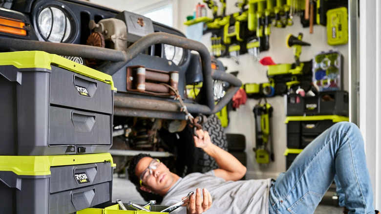 Man fixing car with Ryobi products in the background