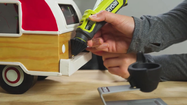 Woman holding Ryobi Glue Pen and putting glue on a toy car