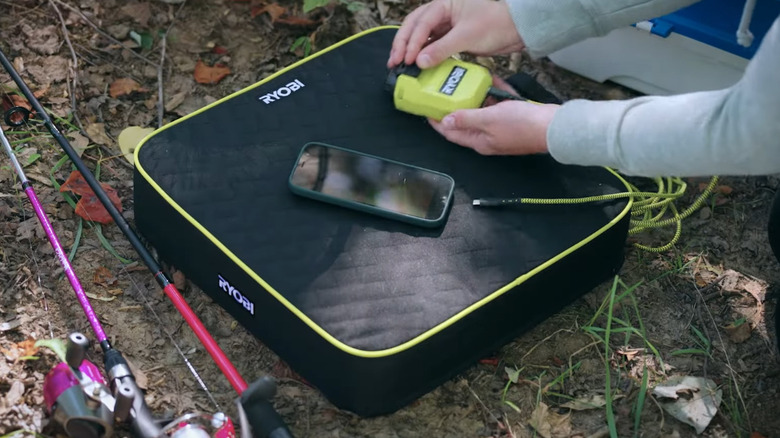 Woman taking out Ryobi heat cushion's power source to charge phone