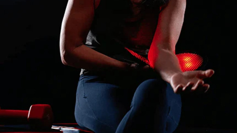 Woman using red light device on her forearm