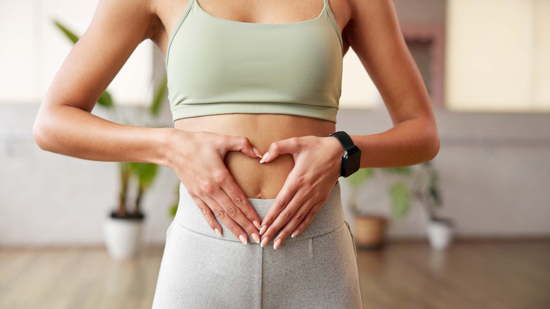 Midsection of woman forming a heart with her hands against her abdomen