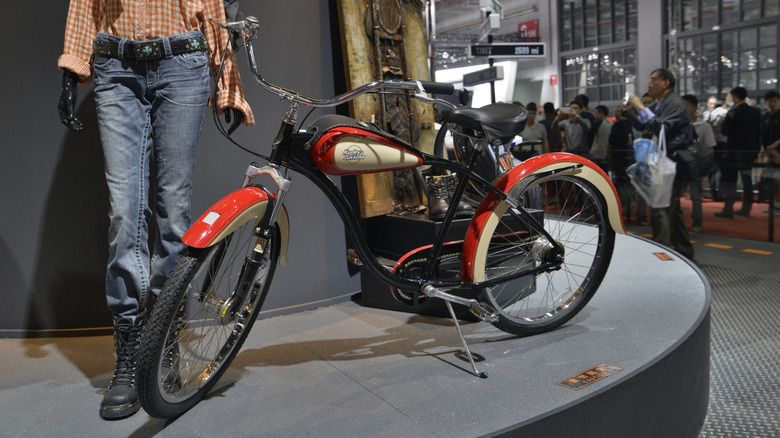 A Harley-Davidson bycicle next to a manequin.
