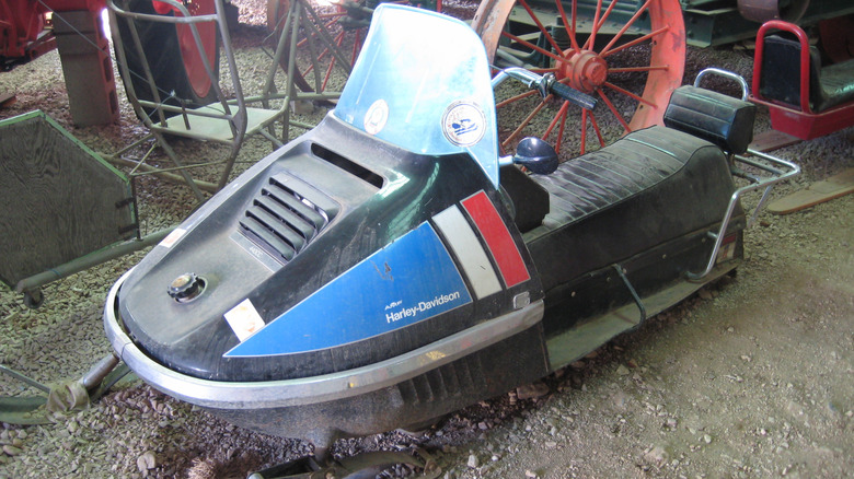 Harley-Davidson snowmobile covered in dust, resting in the dirt.