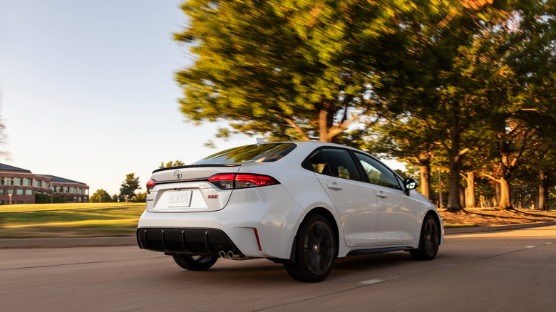 2026 Toyota Corolla driving along country road, rear-right 3/4 view