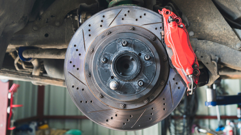 Cross-drilled and slotted brake rotor and caliper installed on car