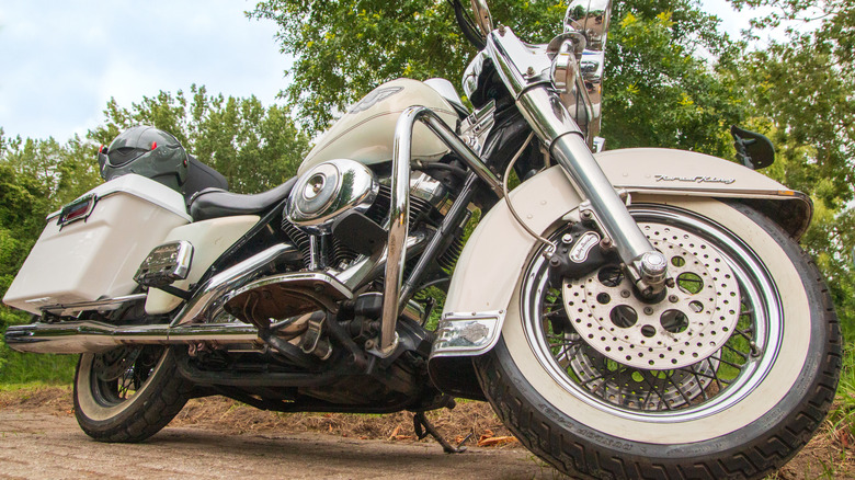 A white Harley-Davidson Road King motorcycle parked outside, with iconic whitewall tires visible.