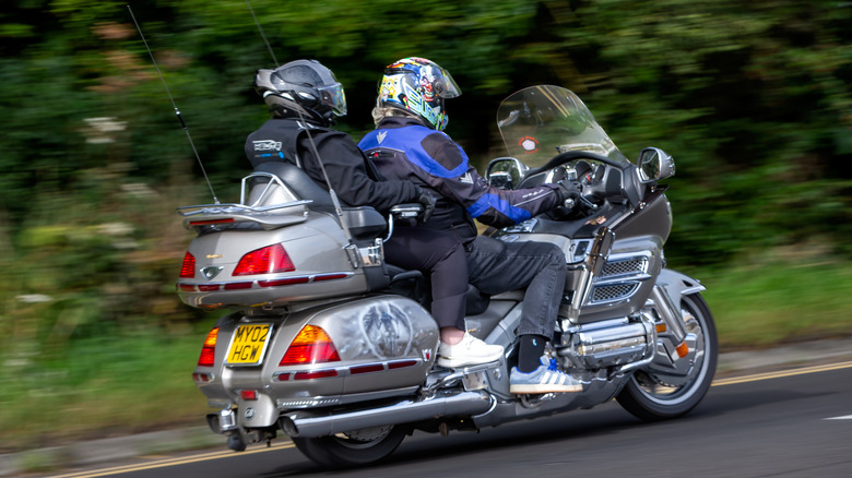 Two riders in full gear riding away from the camera on a silver Honda Gold Wing Tour model from an unknown year.