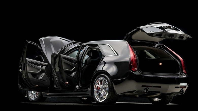 Rear 3/4 view of black Cadillac CTS-V wagon parked in studio with doors and hood open.
