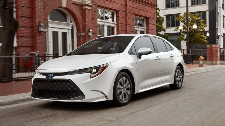 A white 2022 Toyota Corolla Hybrid driving along a city street