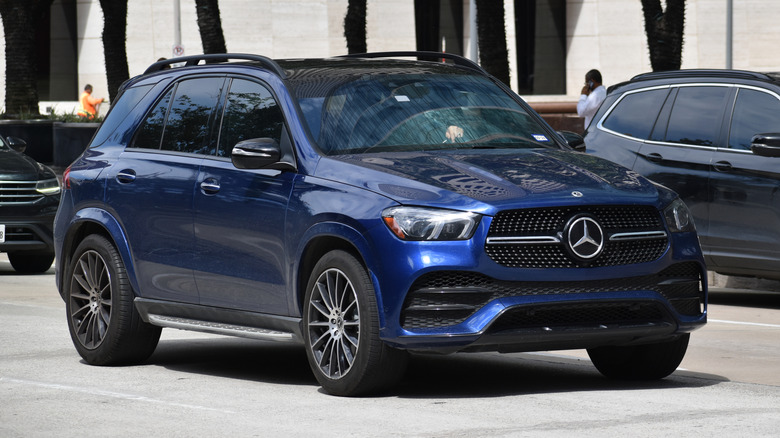 A dark blue Mercedes GLE SUV cruising down an urban street.