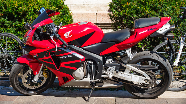 Profile shot of red honda cbr 600 rr motorcycle in front of green shrubs