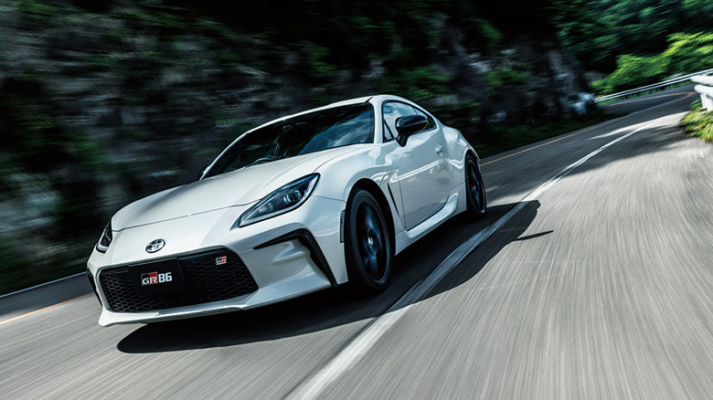2021 Toyota GR86 on winding road, front 3/4 view, white exterior