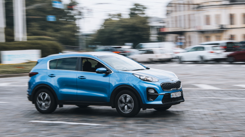 Blue Kia Sportage zipping through city traffic