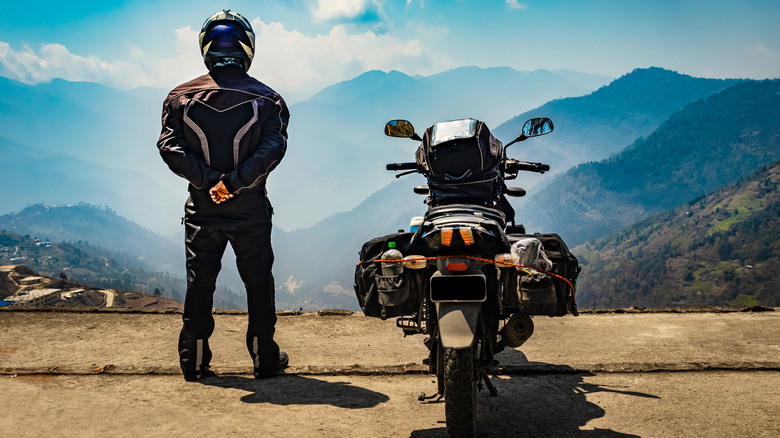 A person wearing a helmet stands next to a motorcycle.