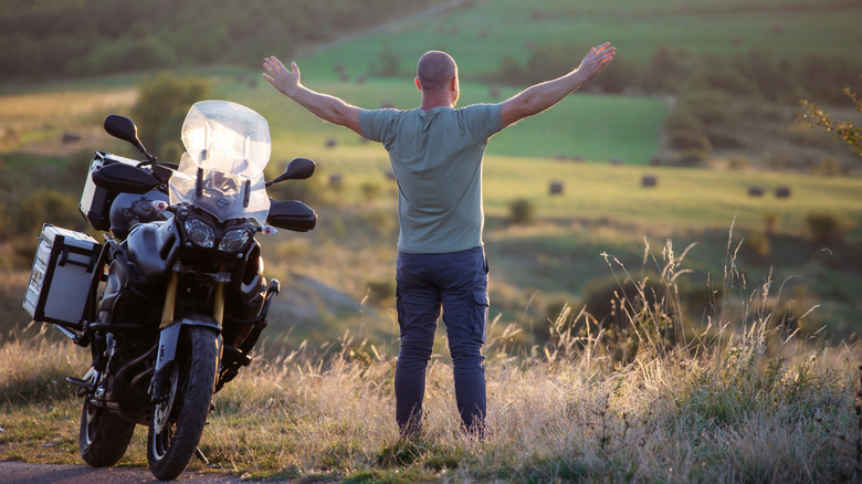 A rider takes a break on the side of the road next to a bike.