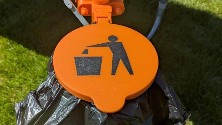 Camping waste bin clamped on table leg