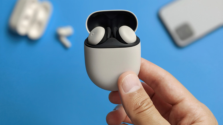 Hand holding white Google Pixel Buds 2 in a charging case