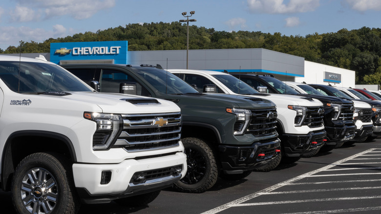 A line of new Silverado pickup trucks parked outside a Chevrolet dealership