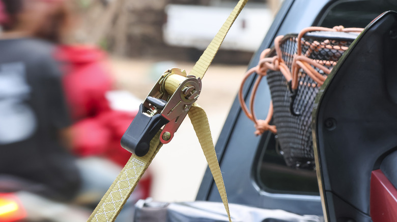 Close up view of yellow ratchet strap securing a load in pickup truck bed.