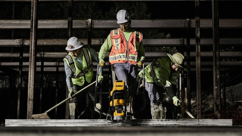 Construction workers using a DeWalt concrete power screed.