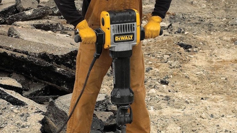 A person using a DeWalt pavement breaker on a construction site